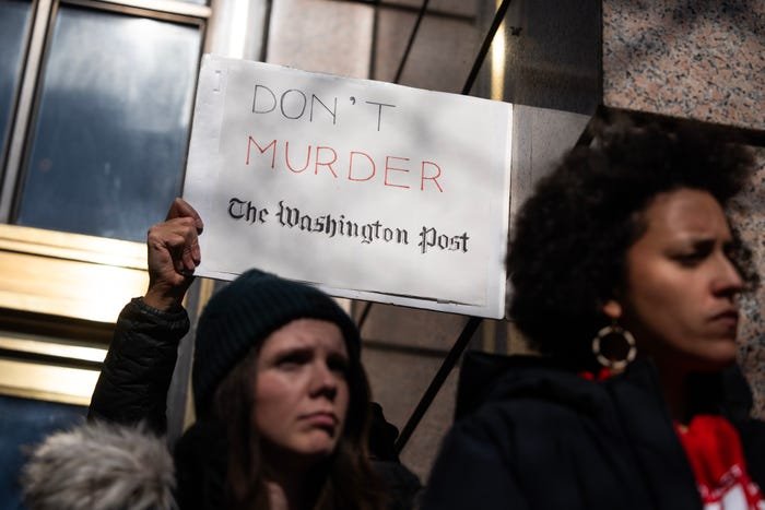 A person holds a protest sign which reads